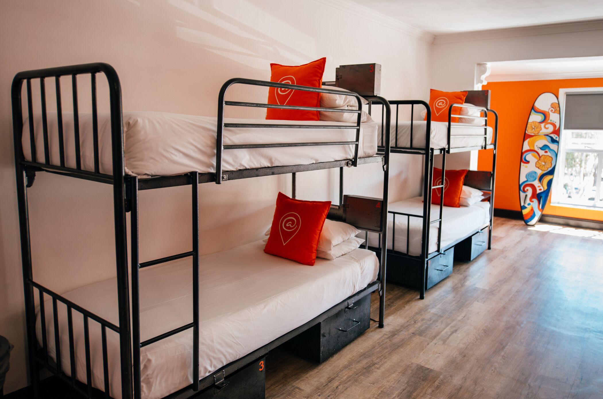 A bunk bed room with two beds, each with a pillow and a small table.