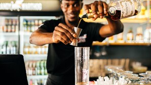 A bartender pouring a drink into a glass. - never at home Green Point (Cape Town)