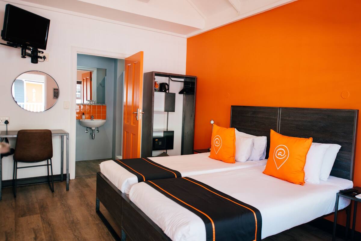 A hotel room with a bed, a desk, a chair, a mirror, and a television.