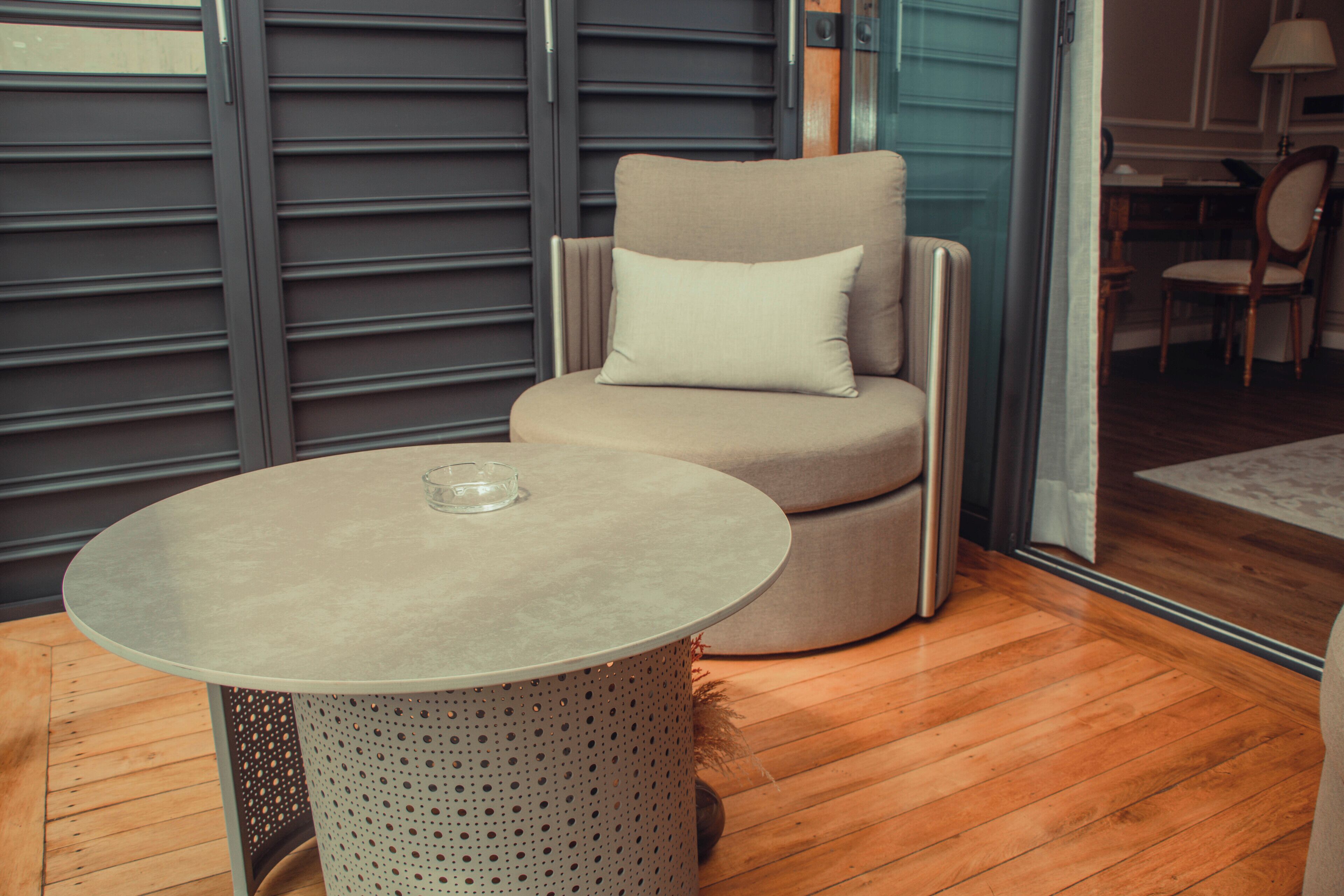 A modern room with a round table, a cushioned chair, and a large window.