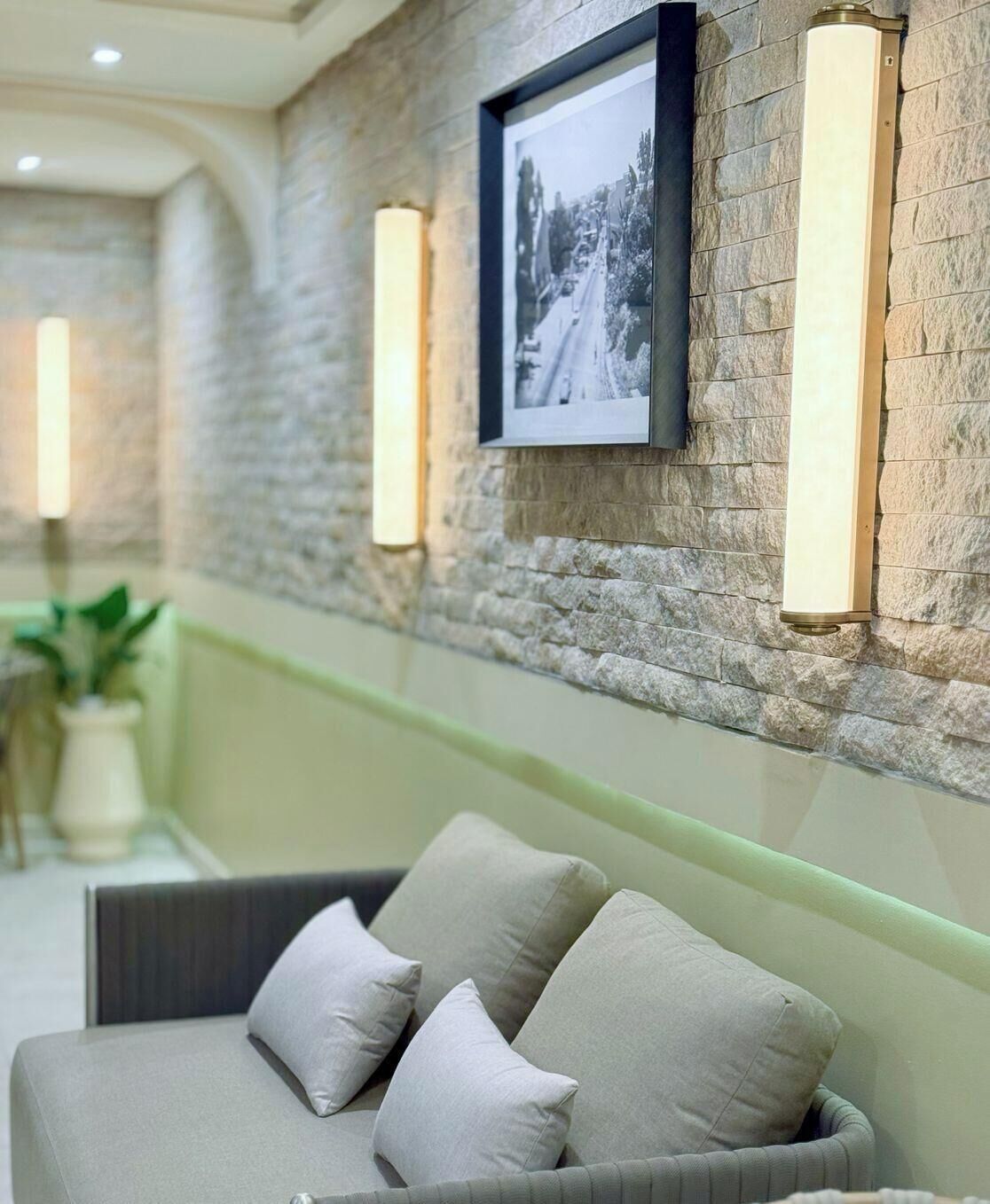 A modern interior with a stone wall, a framed photograph, and a sofa with cushions.