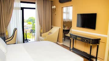 Hotelkamer met een groot bed, een bureau met stoel, een aan de muur bevestigde televisie en uitzicht op het groen door een raam.