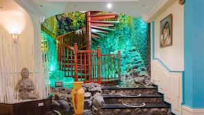 Uma escadaria em espiral com guarda-mão de madeira, cercada por uma parede de rocha e vegetação.