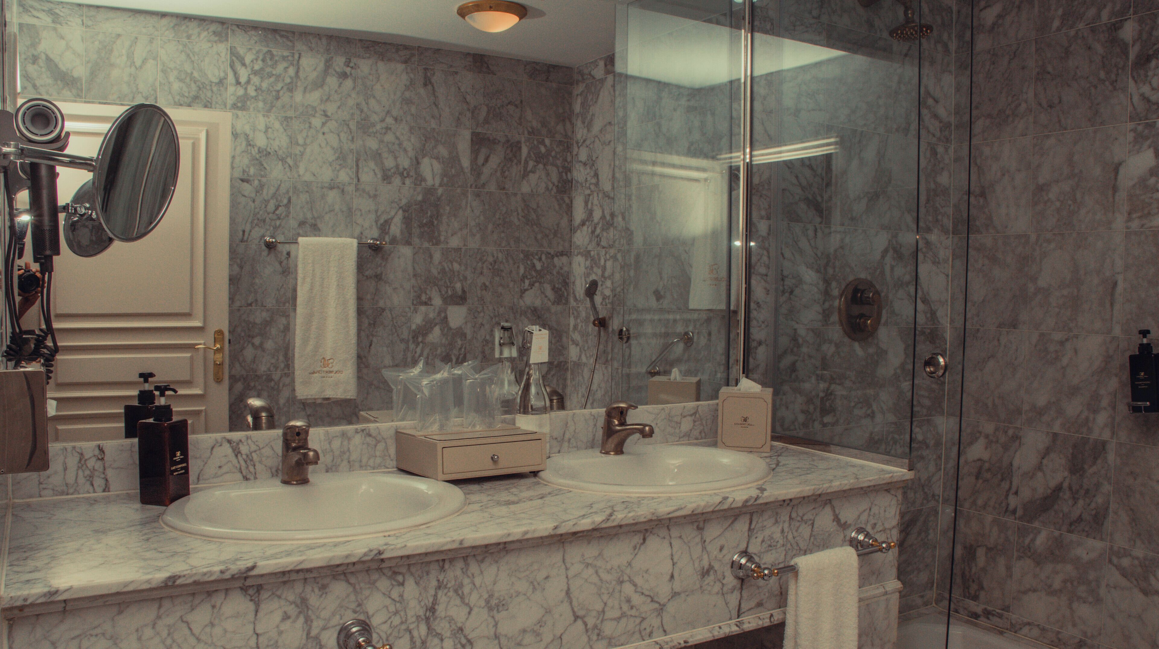 A bathroom with two sinks, a large mirror, and a glass shower enclosure.