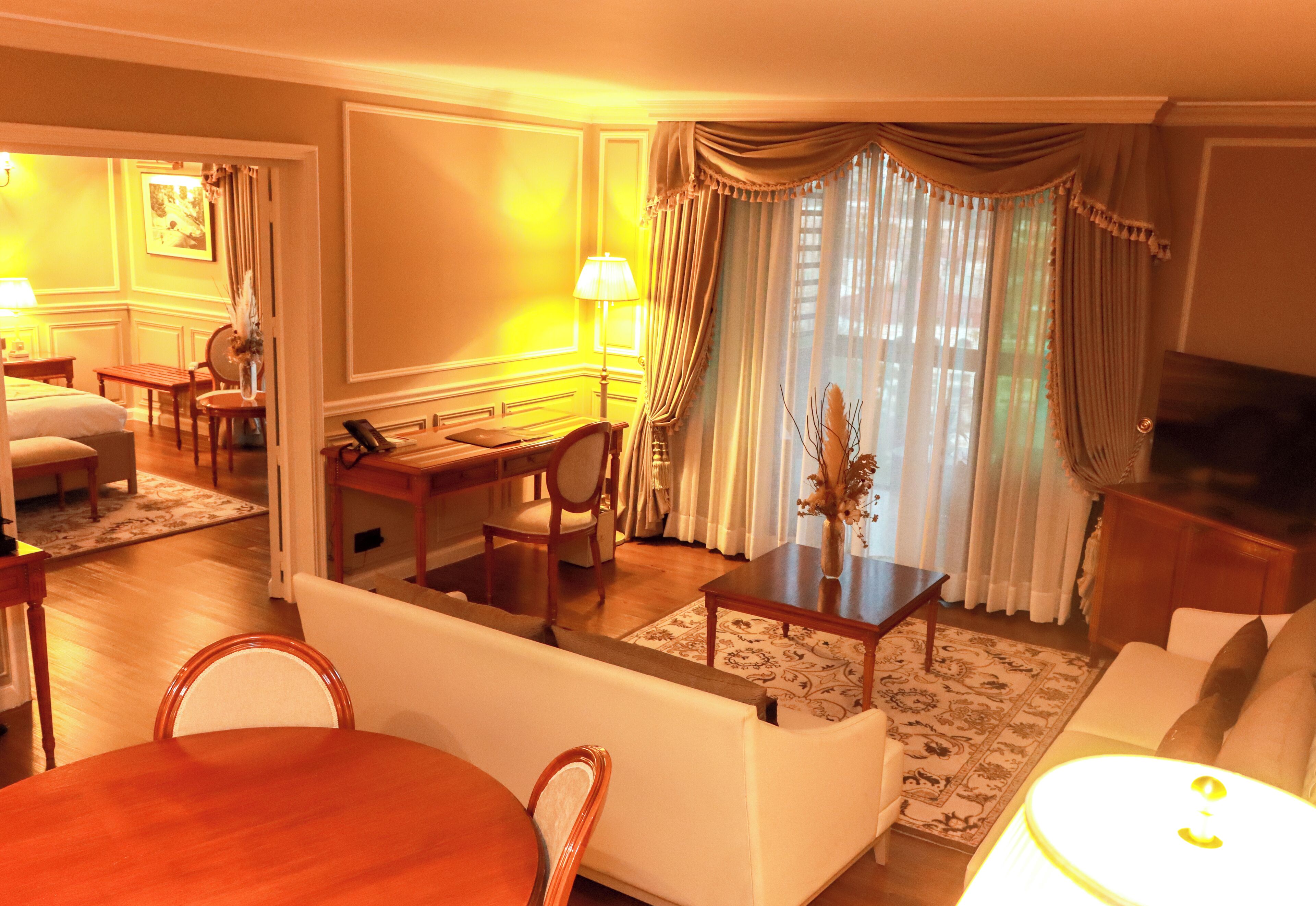 A hotel room with a living area, dining table, and a TV.