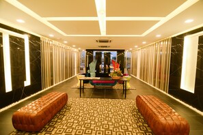 A hotel lobby with a central seating area, a patterned floor, and a modern ceiling design.