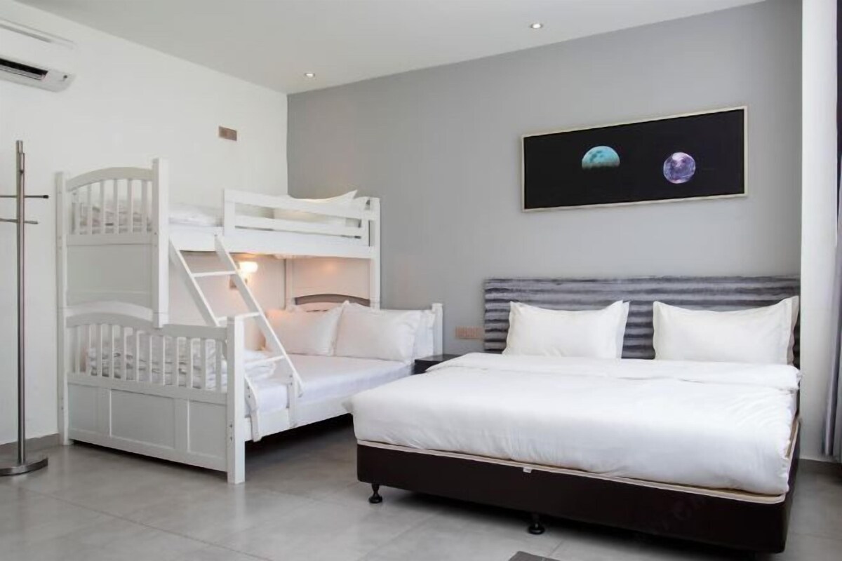 A bedroom with a bunk bed, a single bed, and a framed picture of planets on the wall.