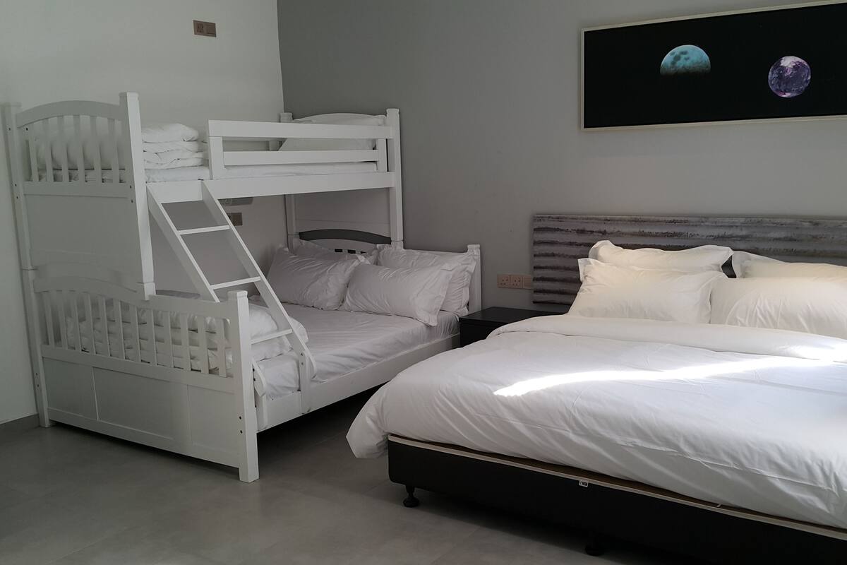 A bedroom with a bunk bed, a single bed, and a nightstand.