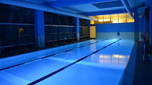 Una piscina con marcas divisorias claras, piso de baldosas y una decoración azul y blanca.