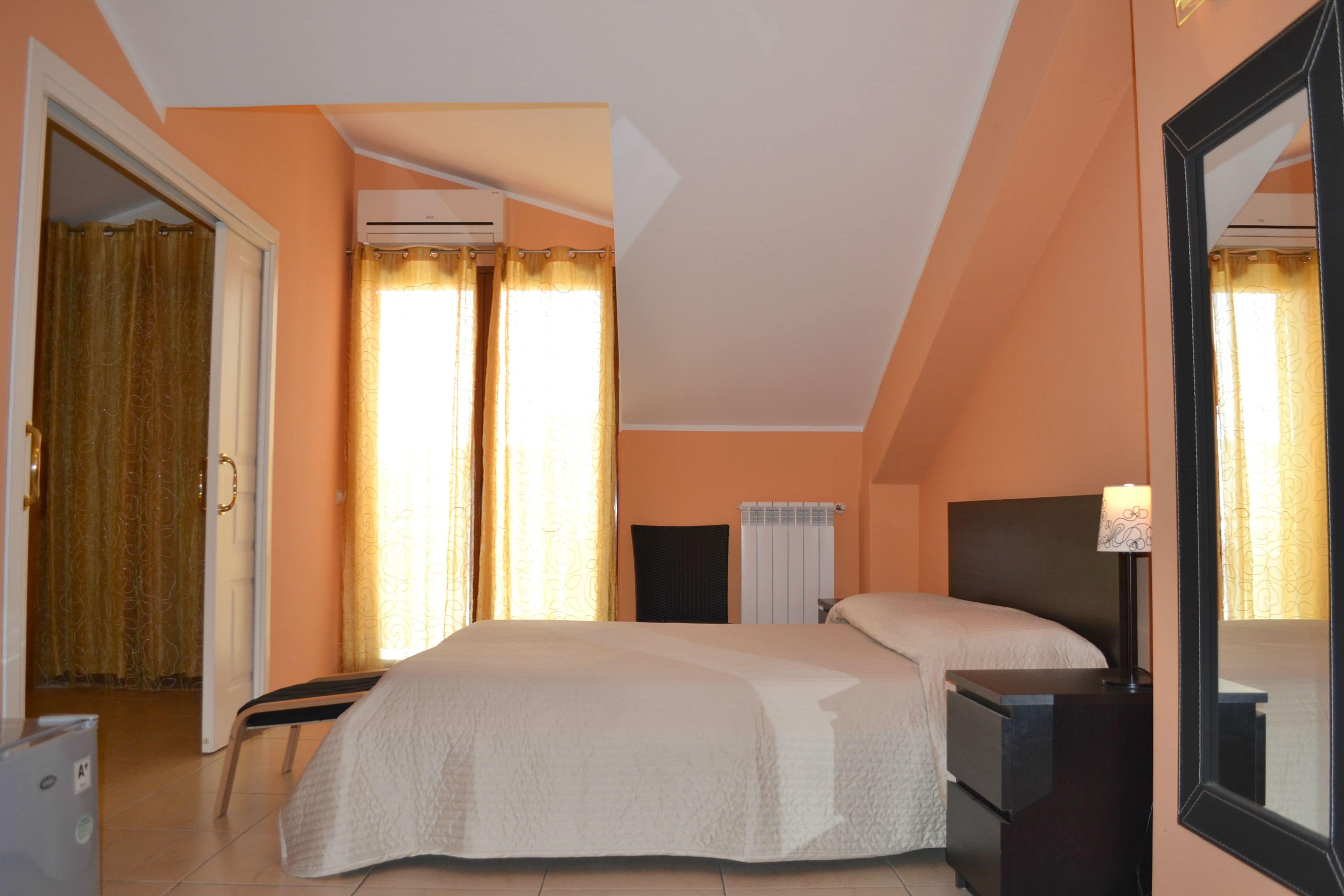A bedroom with a bed, bedside table, lamp, and a mirror.
