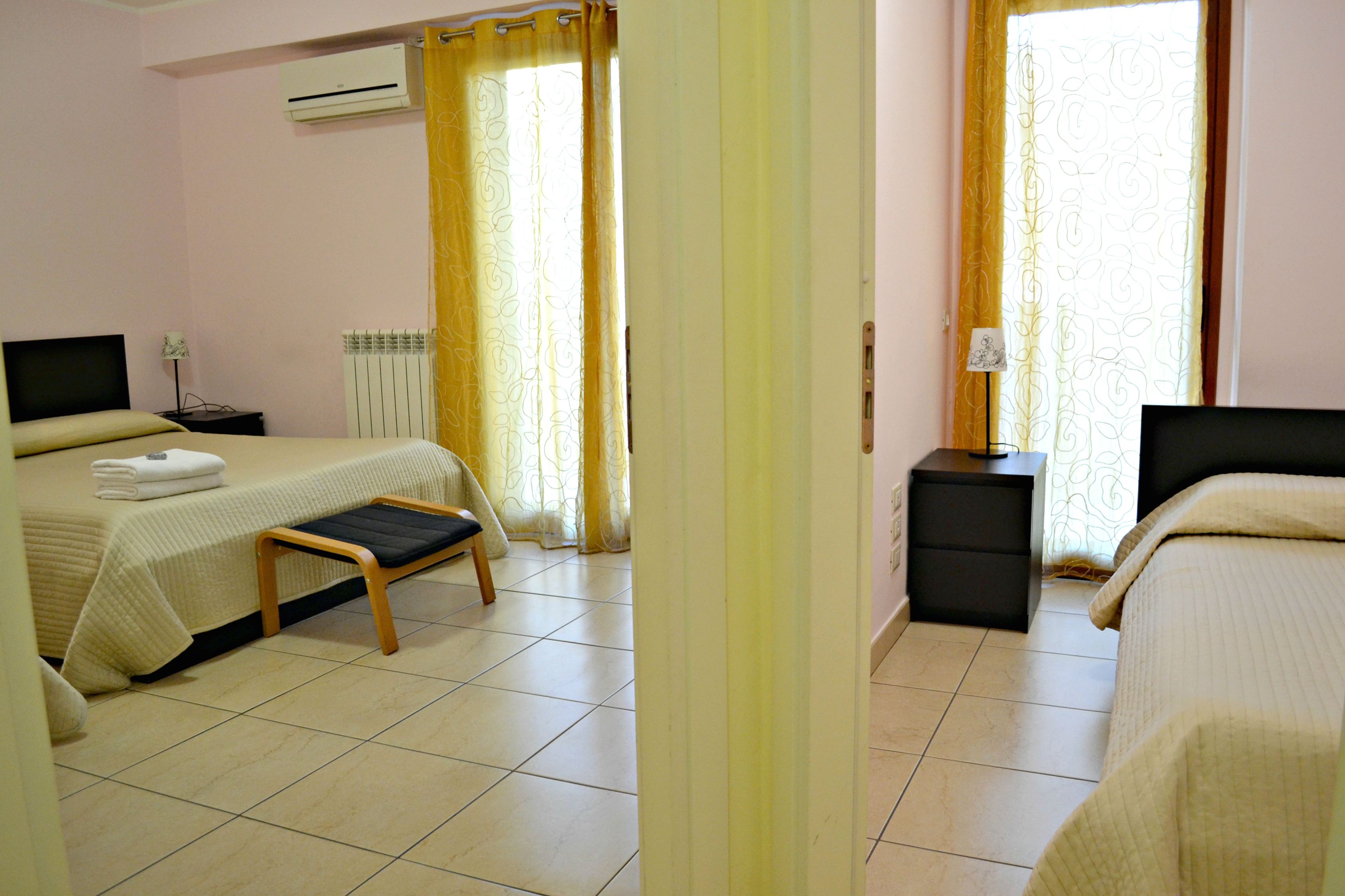 A hotel room with two beds, a desk, a chair, and a TV.