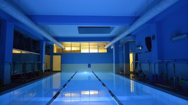Una piscina interior con carriles bien definidos, un techo alto y vista al cielo a través de una ventana.