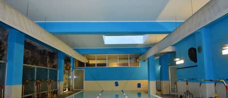 Una piscina interior con carriles delimitados, tragaluces y pared azul.