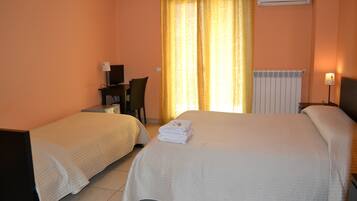 A hotel room with two beds, a desk with a chair, a lamp, and an air conditioning unit.