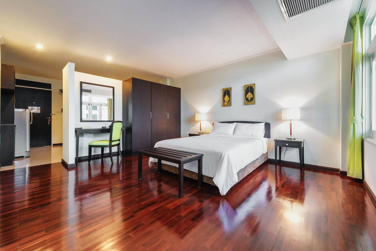 A hotel room with a bed, bedside tables, a desk, and a chair.