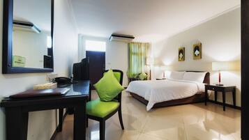Ein Hotelzimmer mit Bett, Schreibtisch mit Telefon, Stuhl, Lampe und Spiegel.