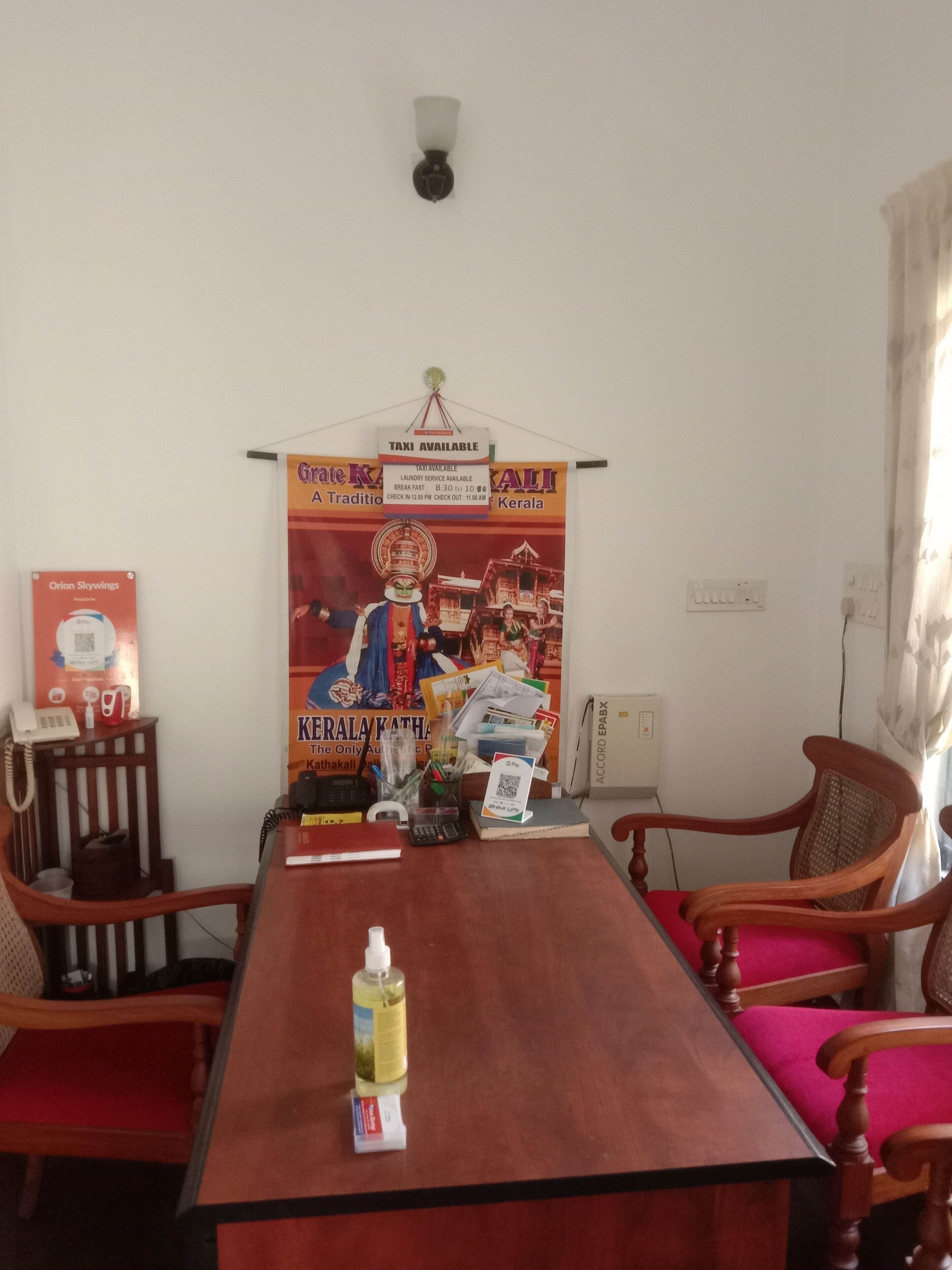 A conference room with a long wooden table, two wooden chairs, a poster on the wall, and a telephone on a small table.