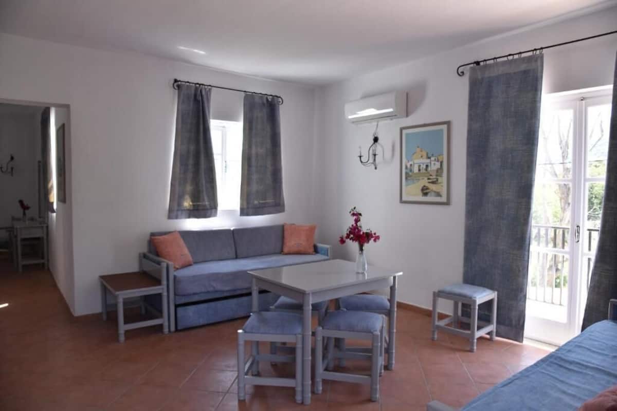 Un salon moderne avec un canapé, une table à manger et des chaises, ainsi qu’un petit tabouret.