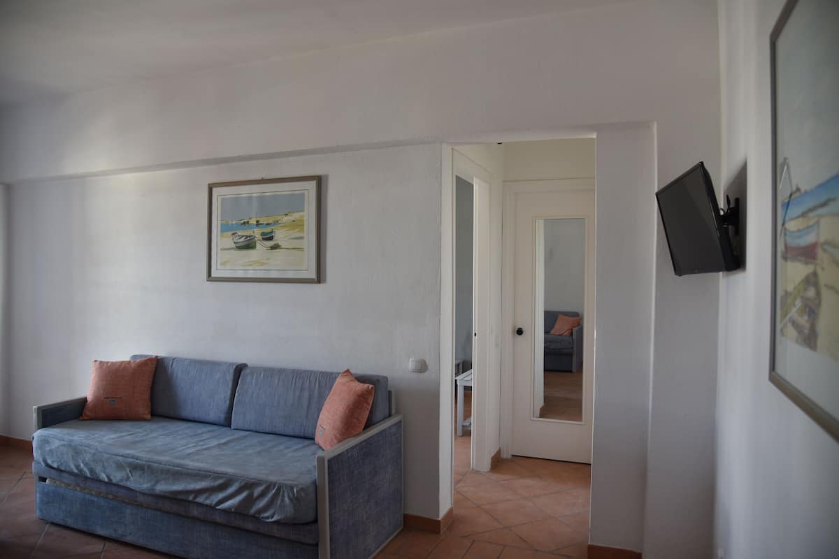 Une pièce avec un canapé, un tableau encadré au mur et un téléviseur fixé au mur.