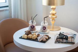 A table with two drinks, a plate of pastries, and a magazine.