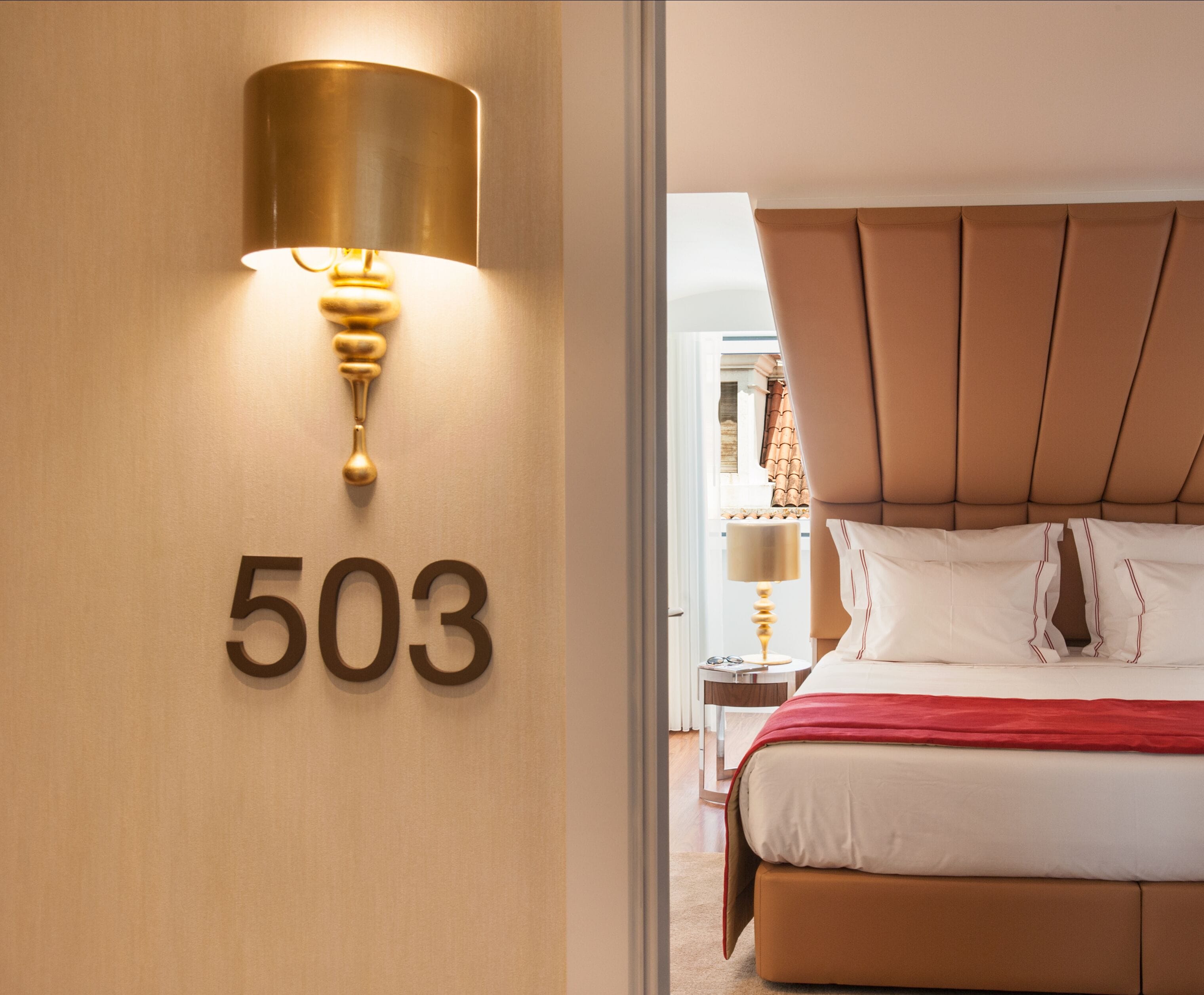 Habitación de hotel con una cama grande, una lámpara de pared y un cartel con el número 503.