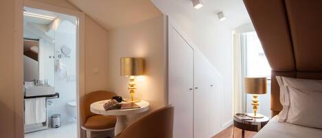Una habitación de hotel moderna con una cama, un escritorio con lámpara, una silla y un armario.