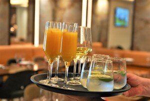A tray with two glasses of orange juice and several small glasses of water with lime slices.