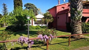 A garden with a red building, a white gazebo, and a lamp post. - Agrialbergo Capalbio La Sugherella (Capalbio)