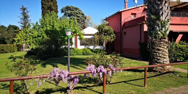 A garden with a red building, a white gazebo, and a lamp post.