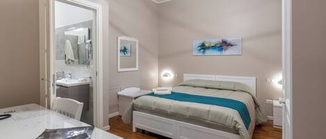 Un dormitorio con cama, mesitas de noche, un escritorio y un espejo.