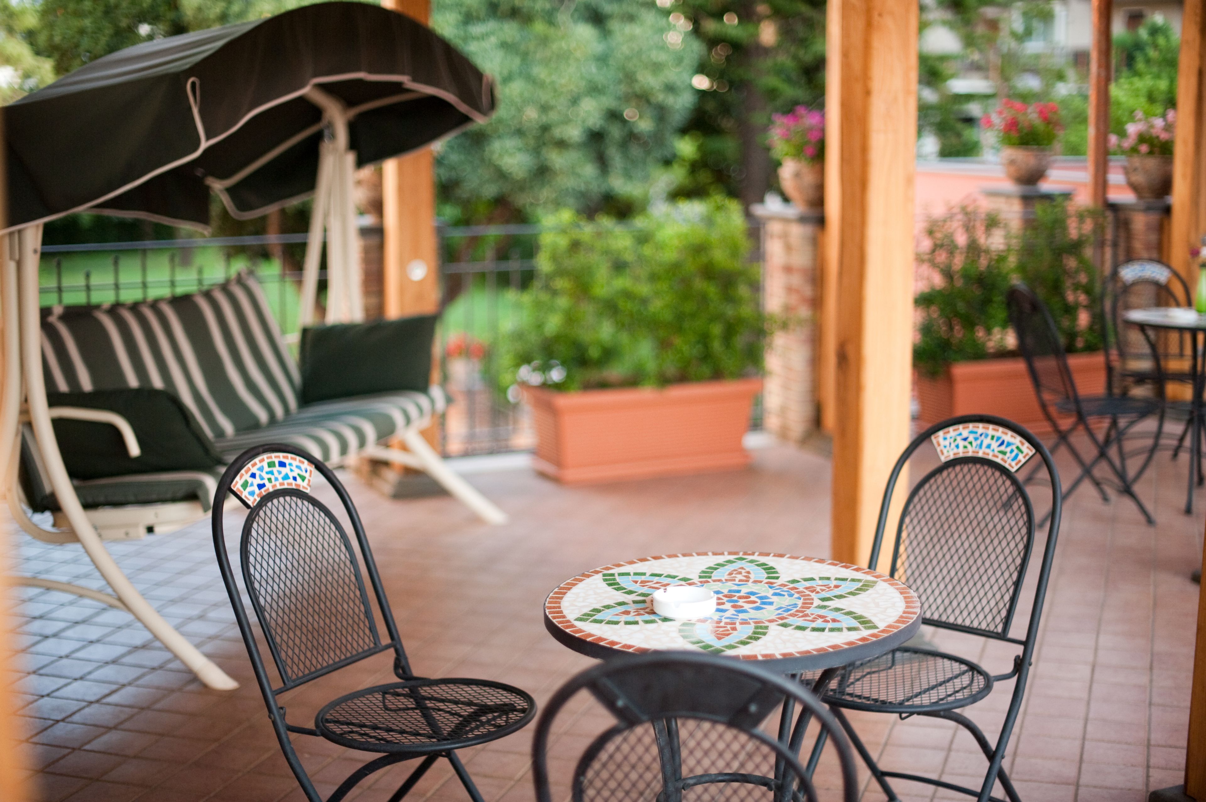 An outdoor patio with a swing chair, a round table, and chairs.