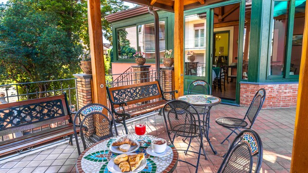 A patio with outdoor seating, a table with food, and a view of a building with a balcony. - Alhambra B&B Guest House di Charme (Giarre)