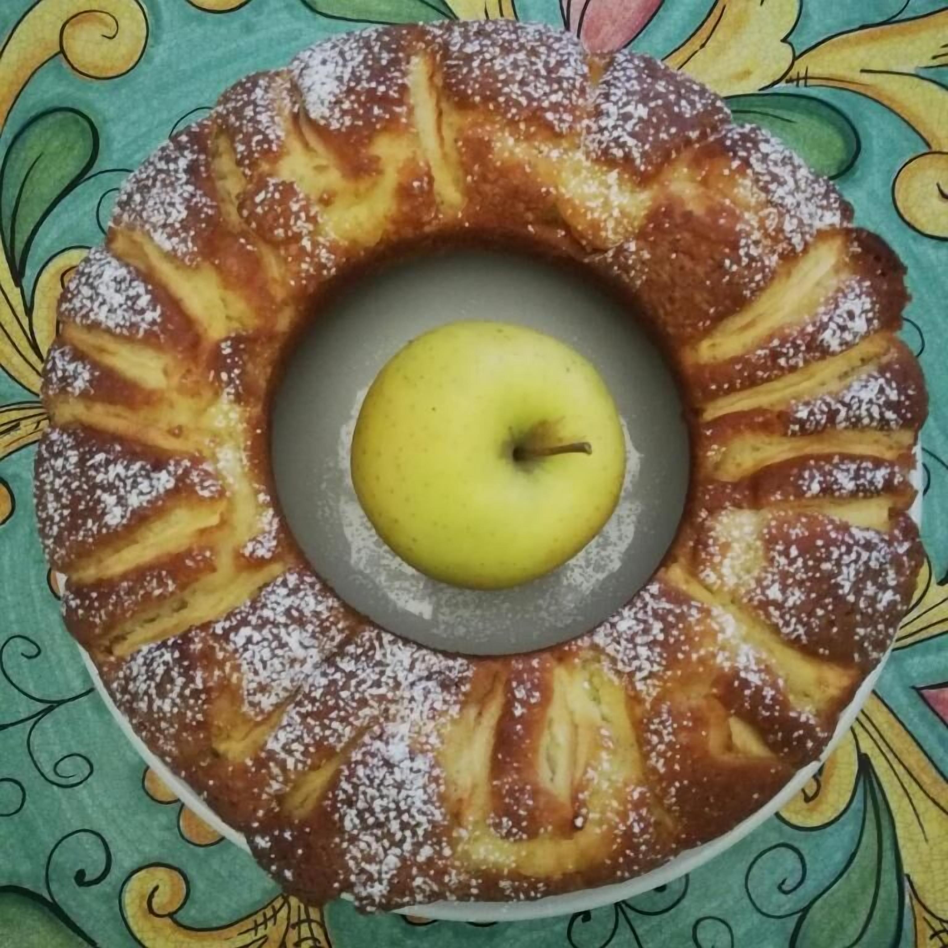 Ein Gugelhupf mit einem Apfel in der Mitte, bestäubt mit Puderzucker.