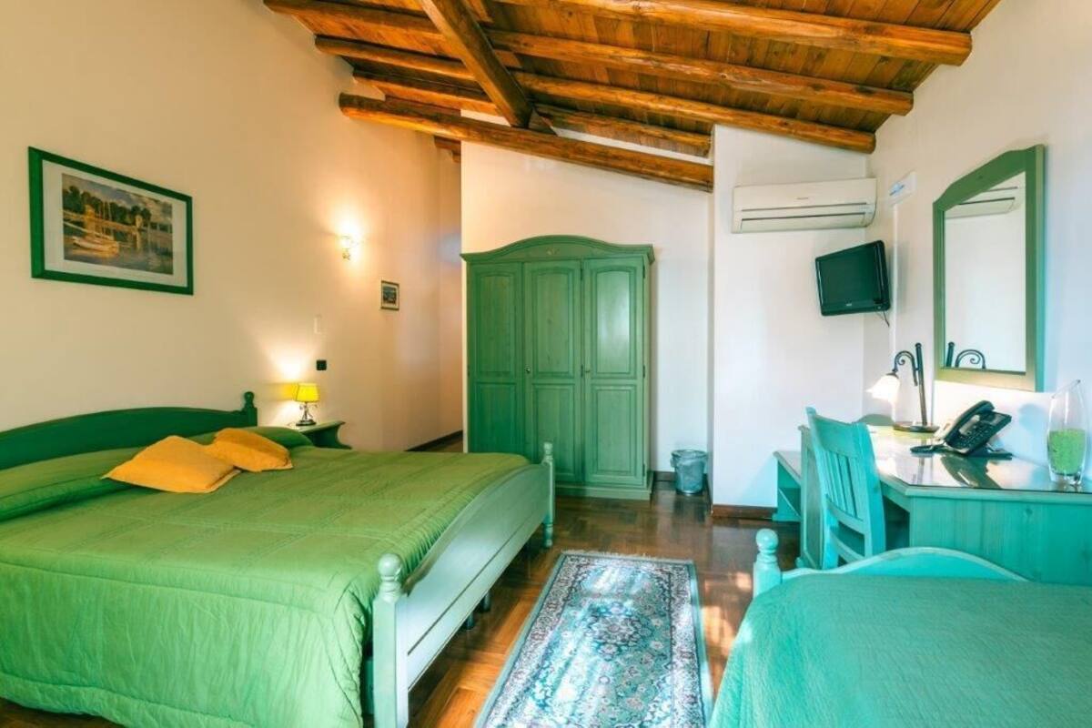 Una habitación con una cama, un escritorio, un armario verde y un televisor.