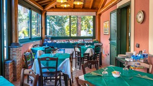 A restaurant with multiple tables and chairs, large windows, and a wooden ceiling. - Alhambra B&B Guest House di Charme (Giarre)