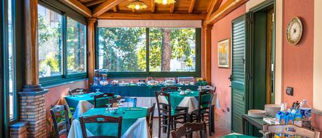 Un restaurant doté de nombreuses tables et chaises, de grandes fenêtres et d’un plafond en bois.