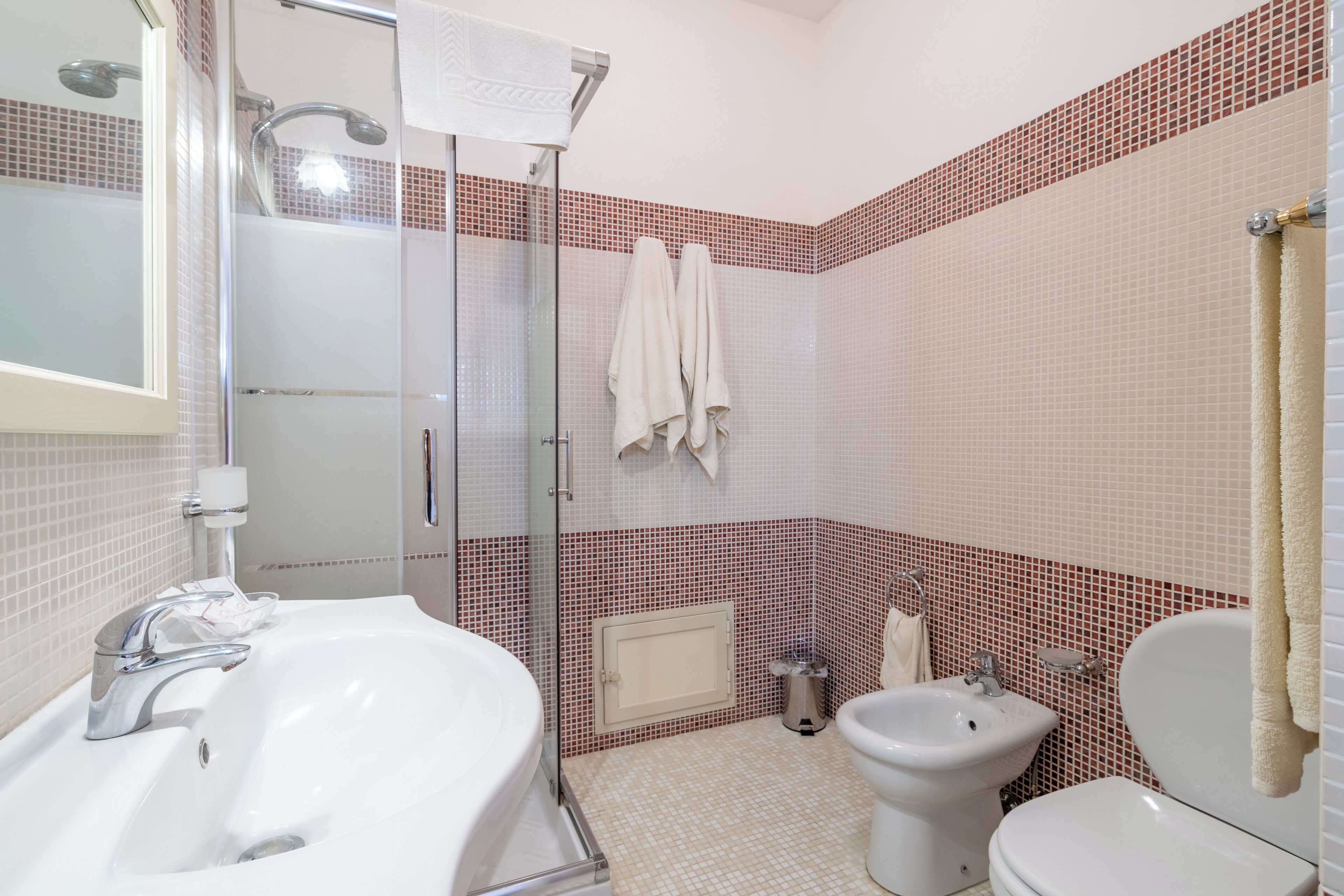 Un baño con ducha de vidrio, un lavamanos blanco, un bidé y un inodoro.