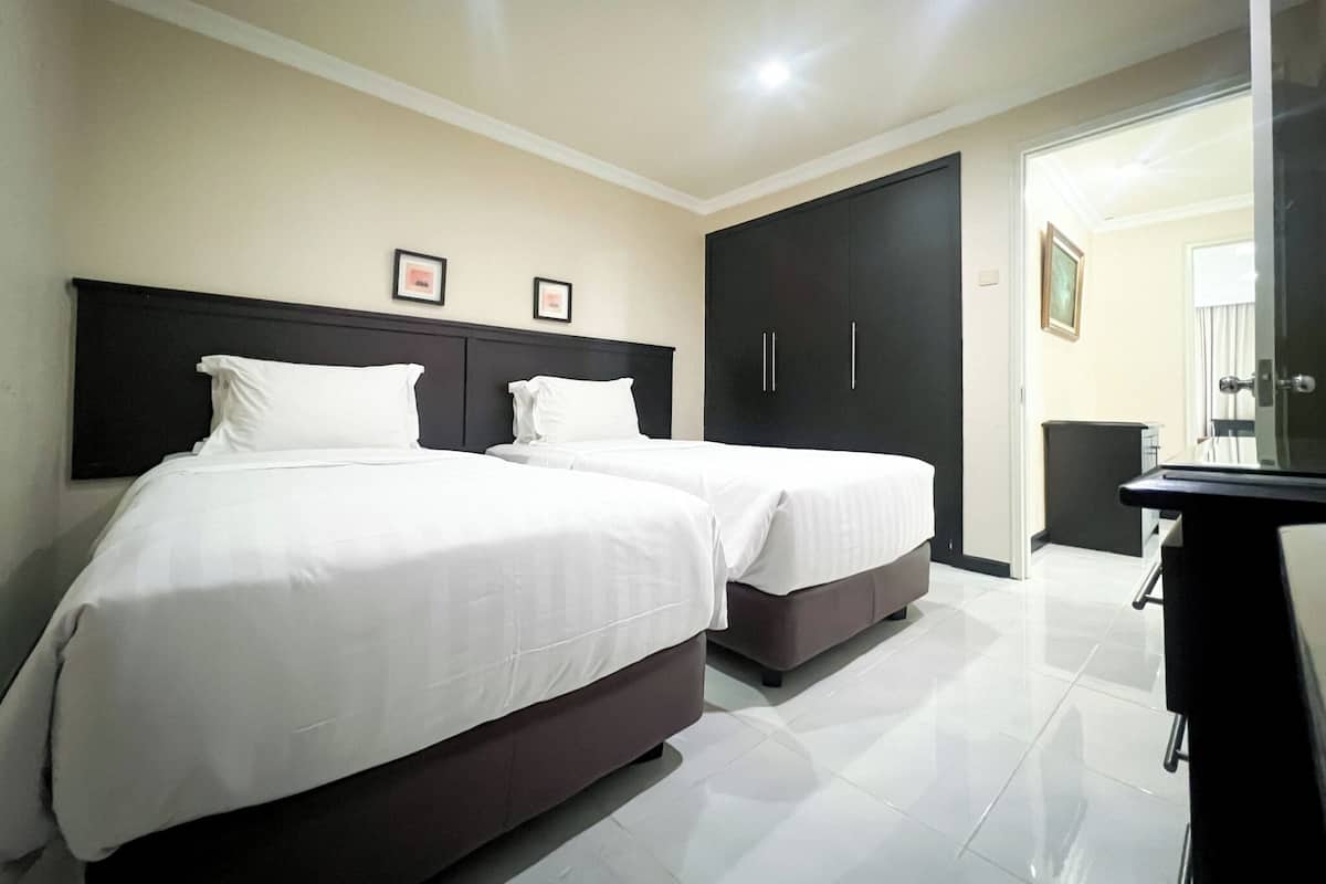 A hotel room with two beds, a wardrobe, and a TV.