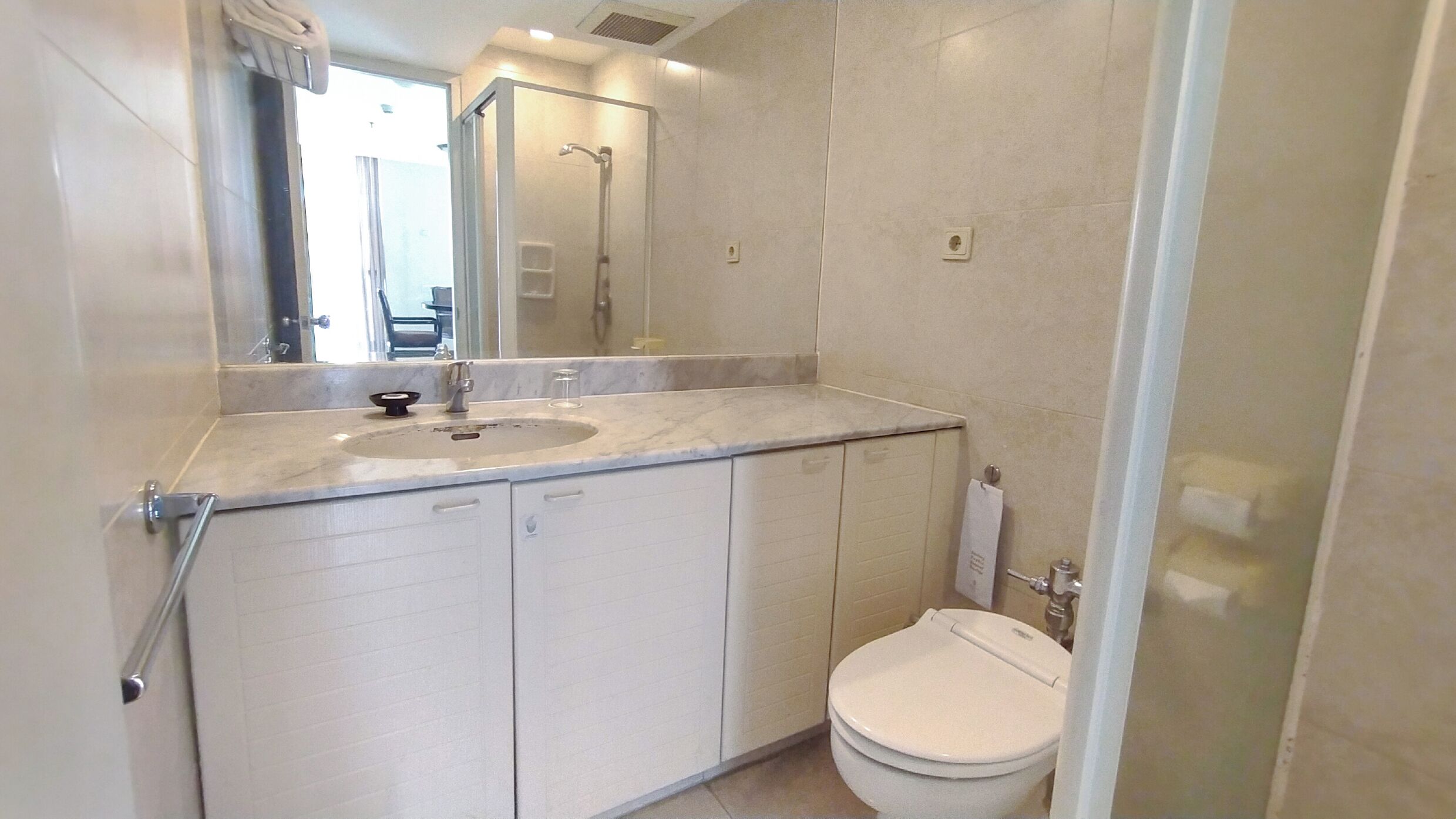A bathroom with a sink, mirror, toilet, and cabinets.