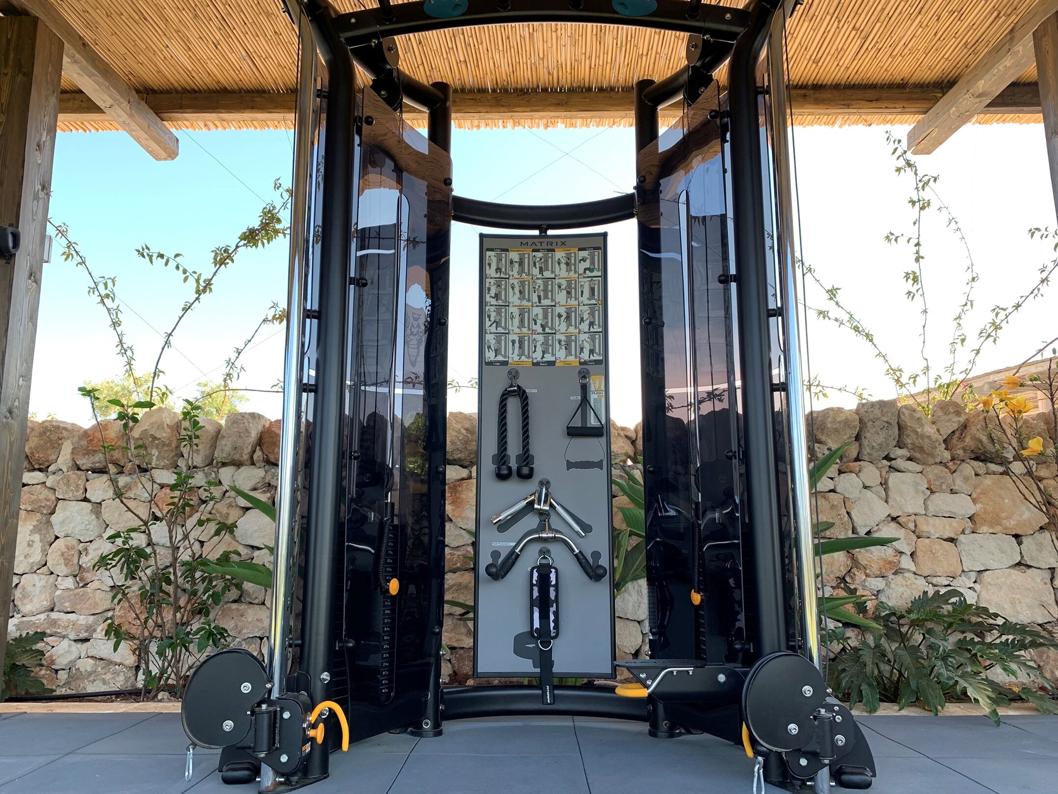 Ein Fitnessraum mit Spiegelwand, Gewichte und einer Wand aus Stein im Hintergrund.