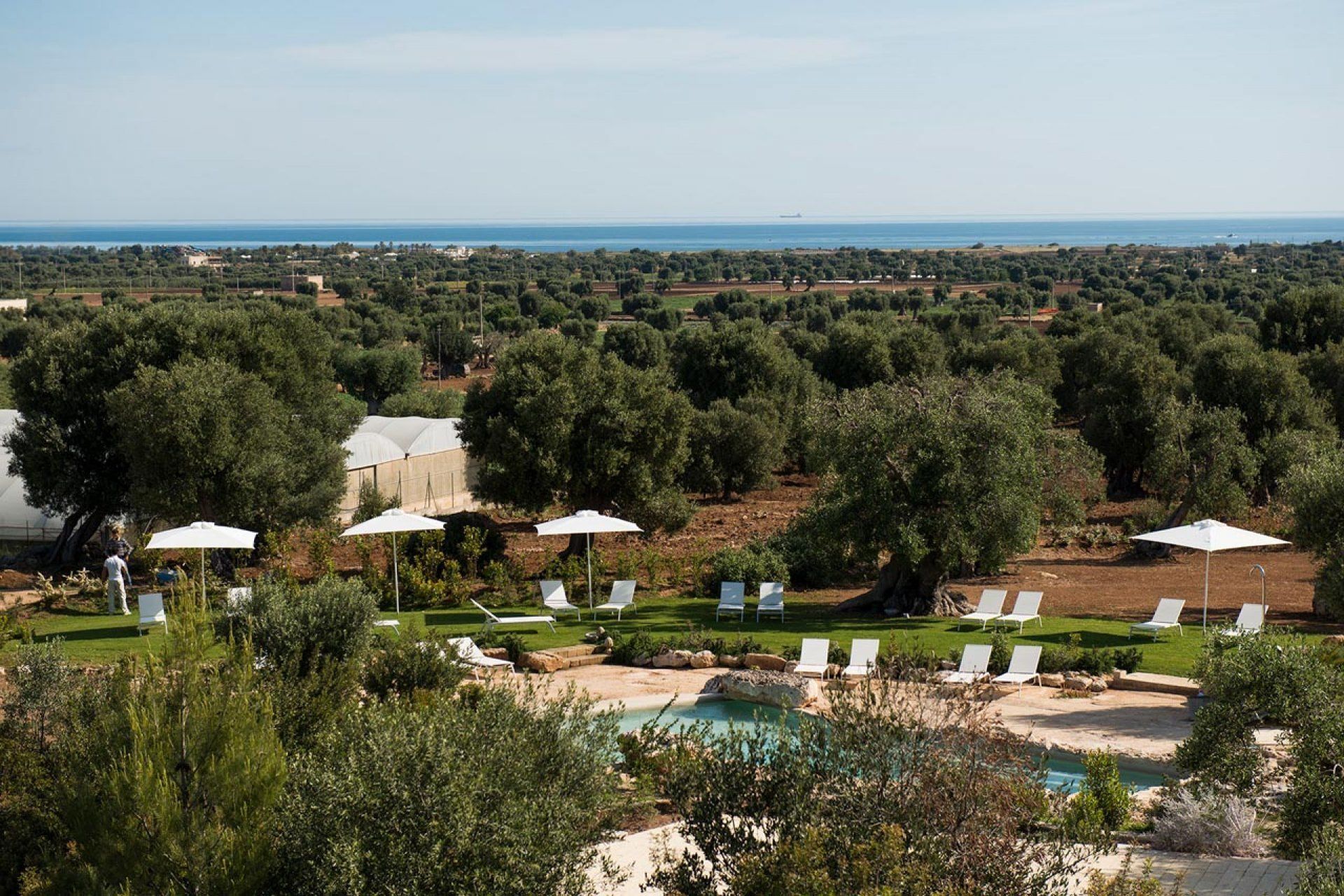 Un complexe hôtelier doté d’une piscine, de chaises longues et offrant une vue sur la mer.
