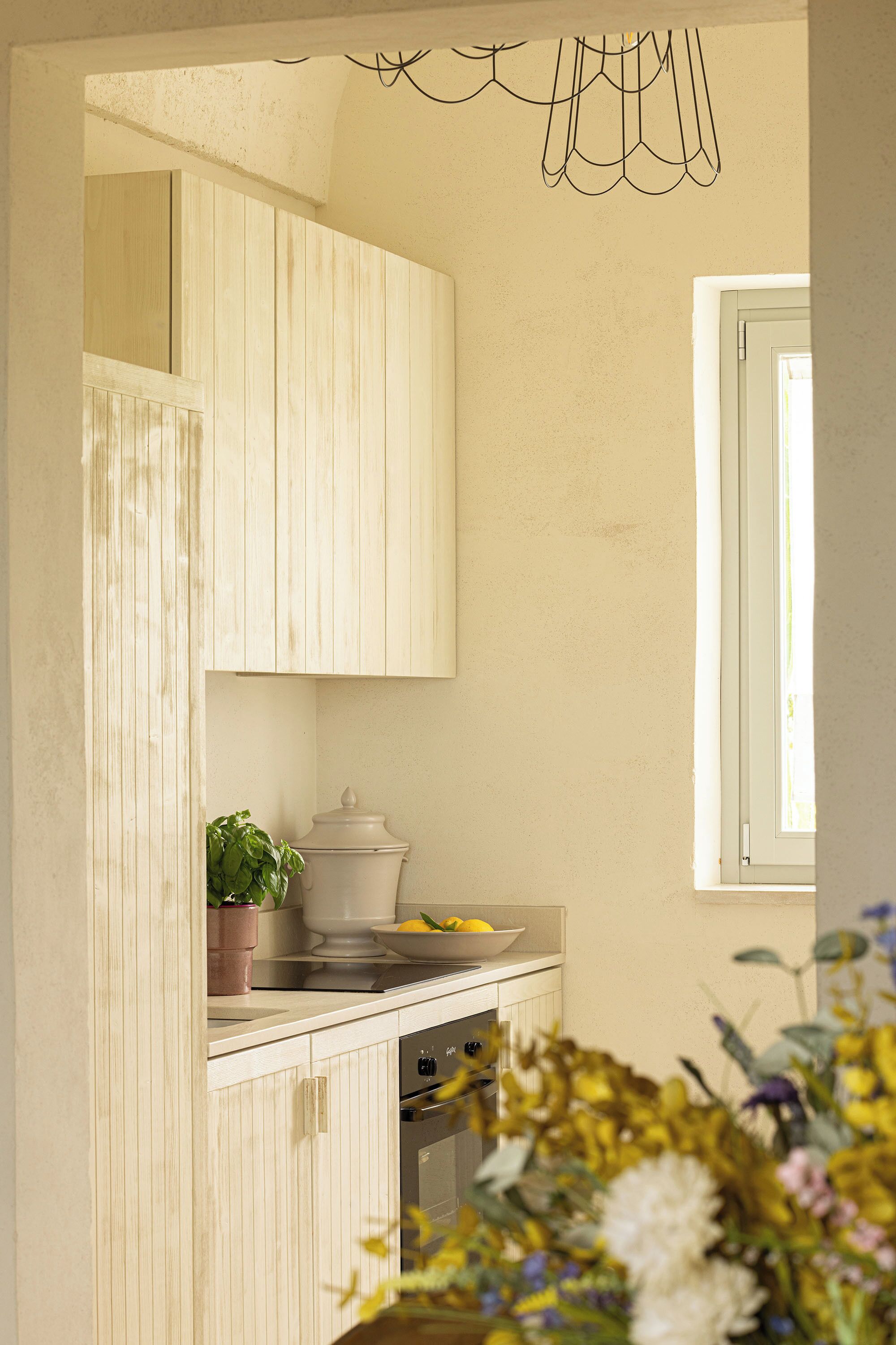 A kitchen with wooden cabinets, a window, and a hanging light fixture.