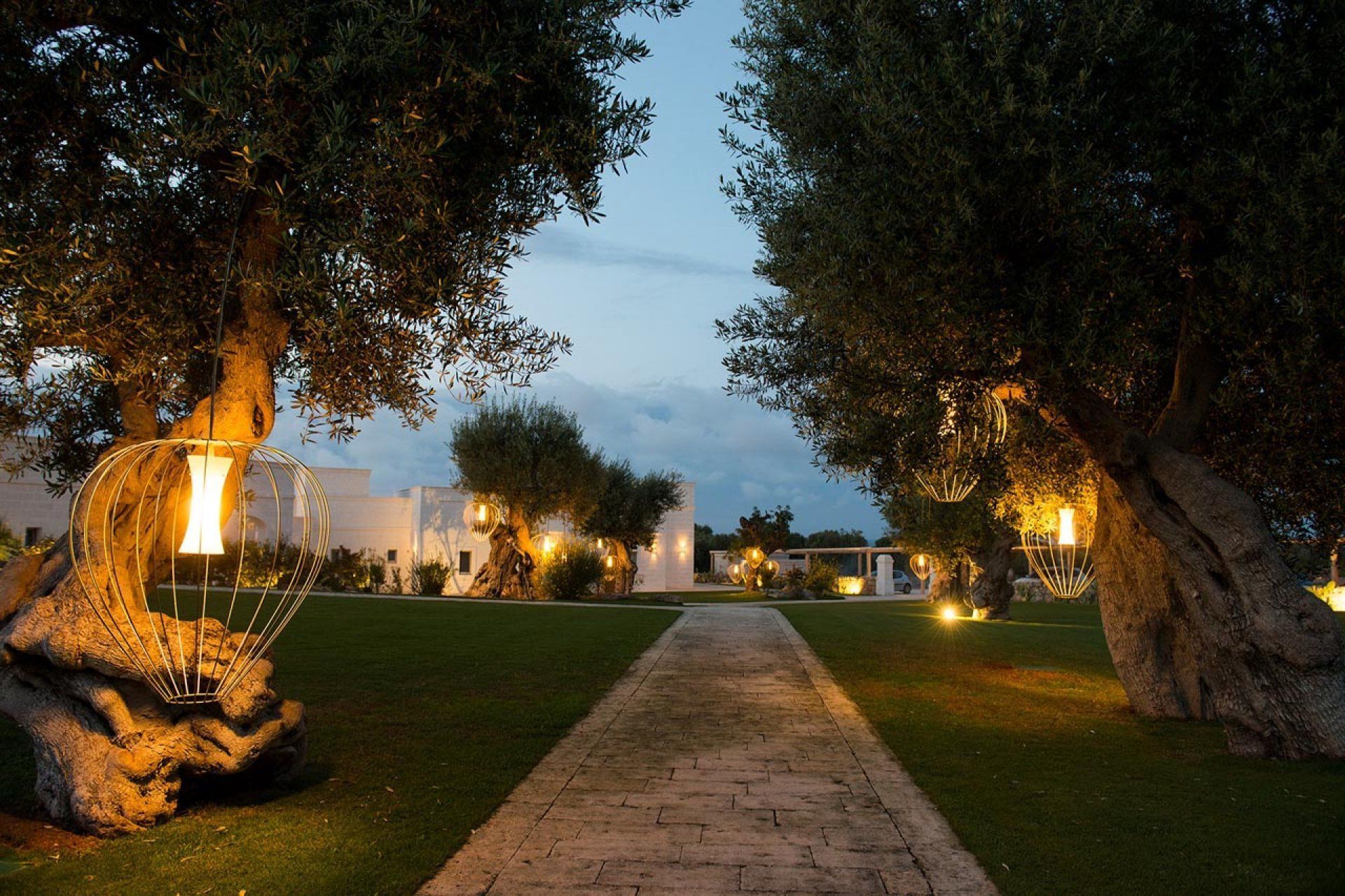 A pathway leading through a landscaped area with trees and outdoor lighting.