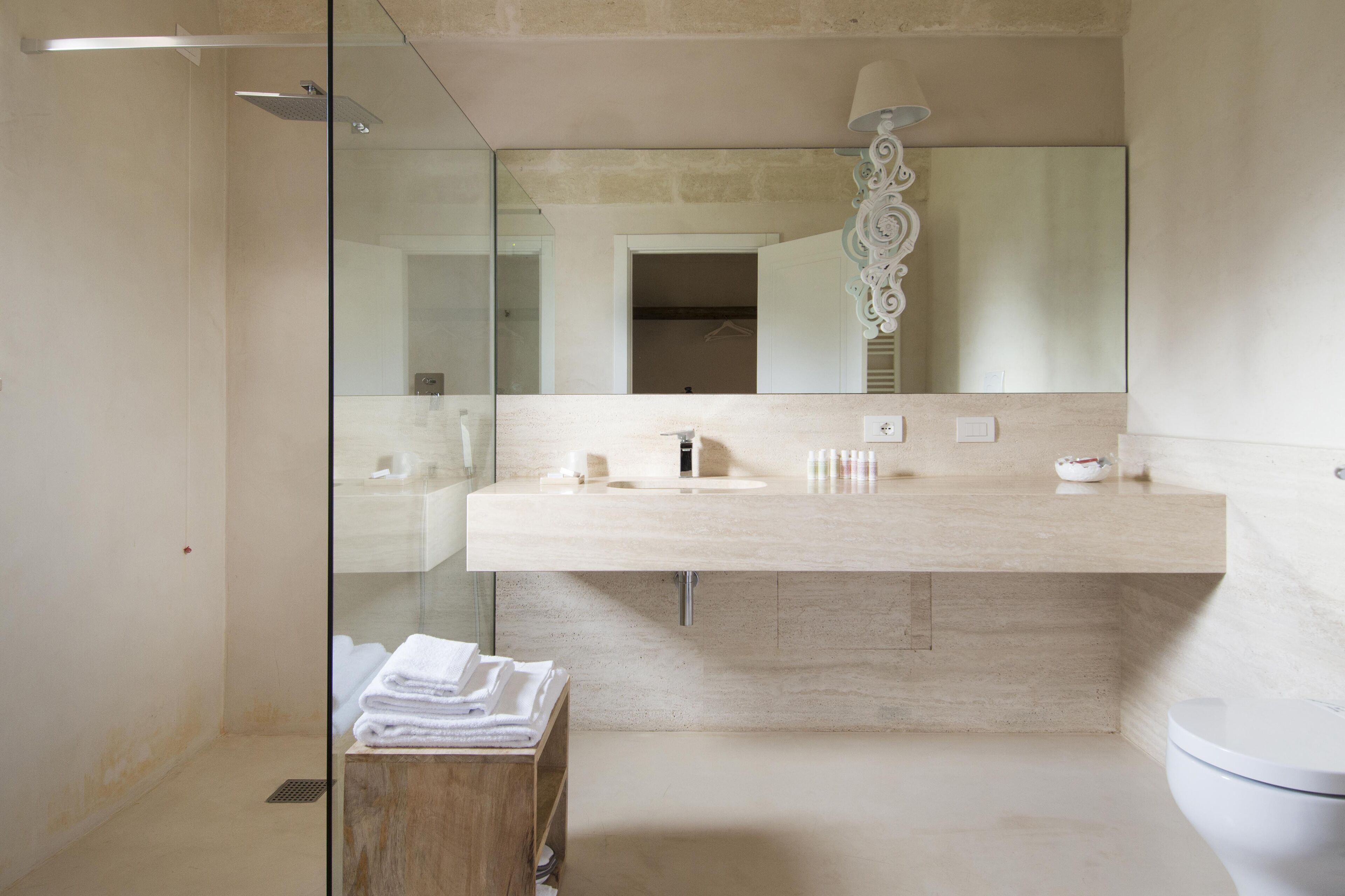 Un baño moderno con cabina de ducha de vidrio, un espejo grande y una encimera color beige.