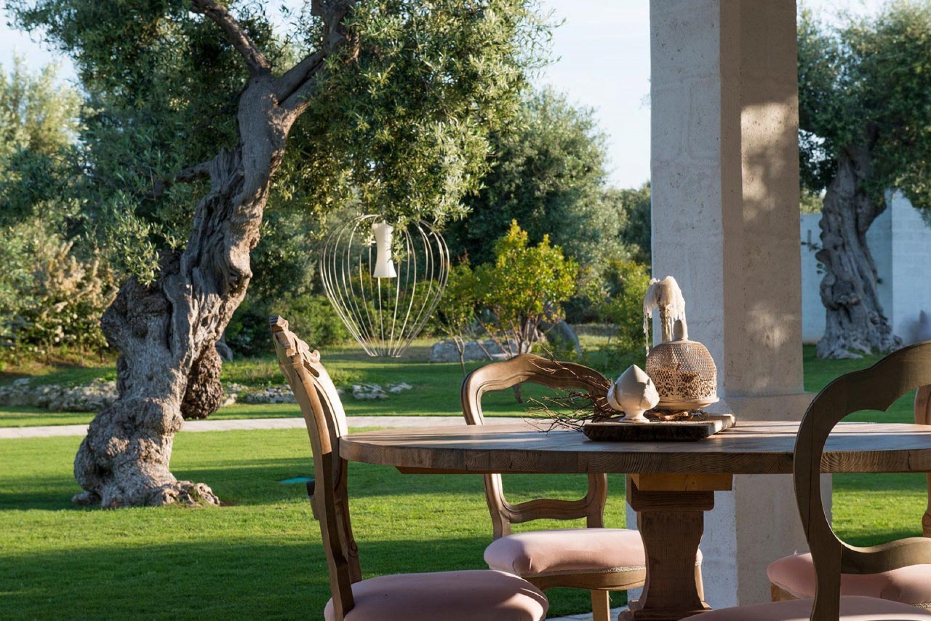 Un área de comedor al aire libre con mesa y sillas, rodeada de follaje y árboles.