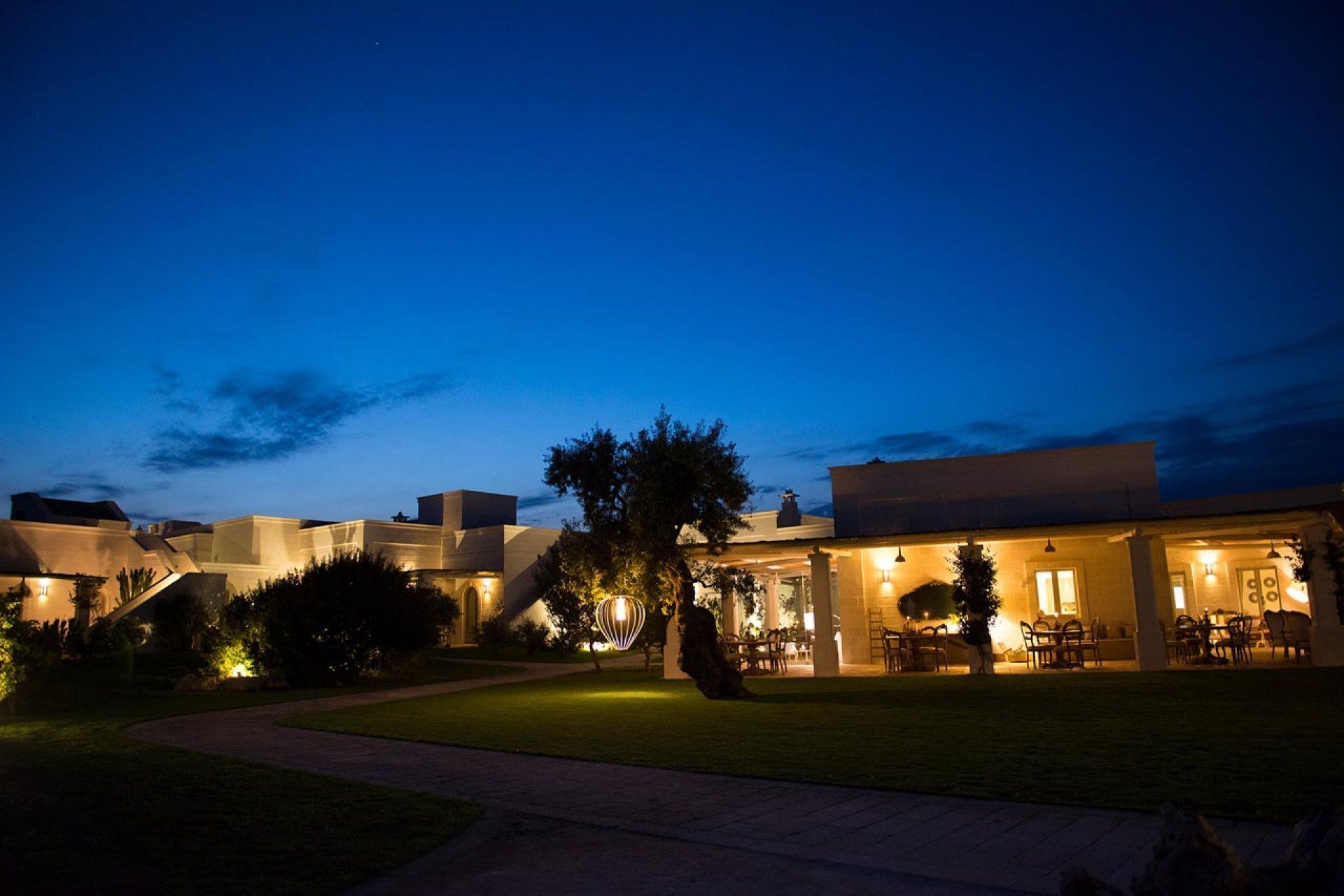 Un hotel moderno con una zona de estar exterior bien iluminada y vistas despejadas del paisaje circundante.