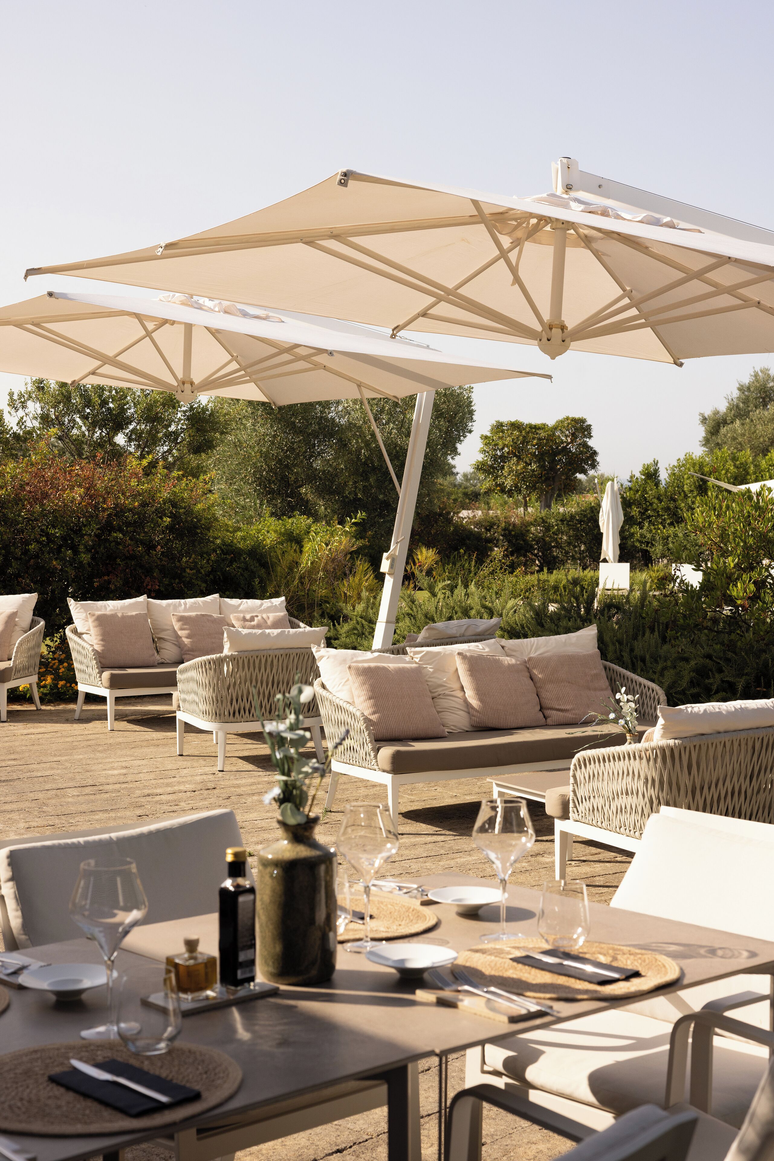 An outdoor seating area with wicker furniture, a table set for dining, and a large canopy umbrella.