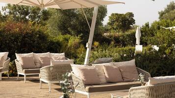 An outdoor seating area with wicker furniture, a table set for dining, and a large canopy umbrella.