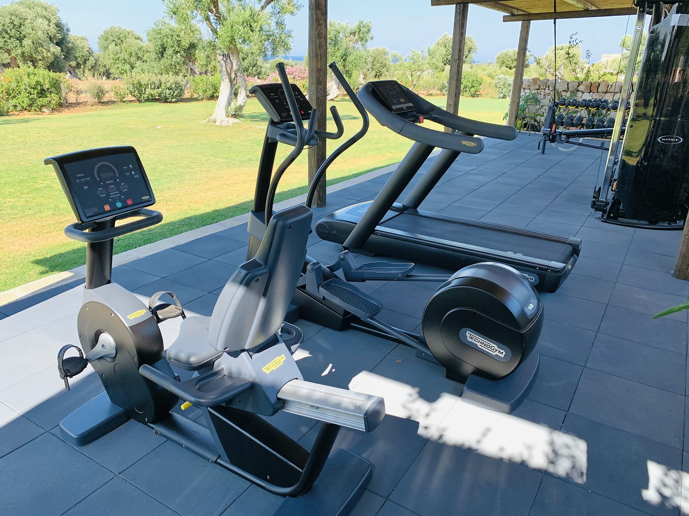 Ett utomhusgym med träningsutrustning, inklusive en motionscykel, en crosstrainer och löpband.