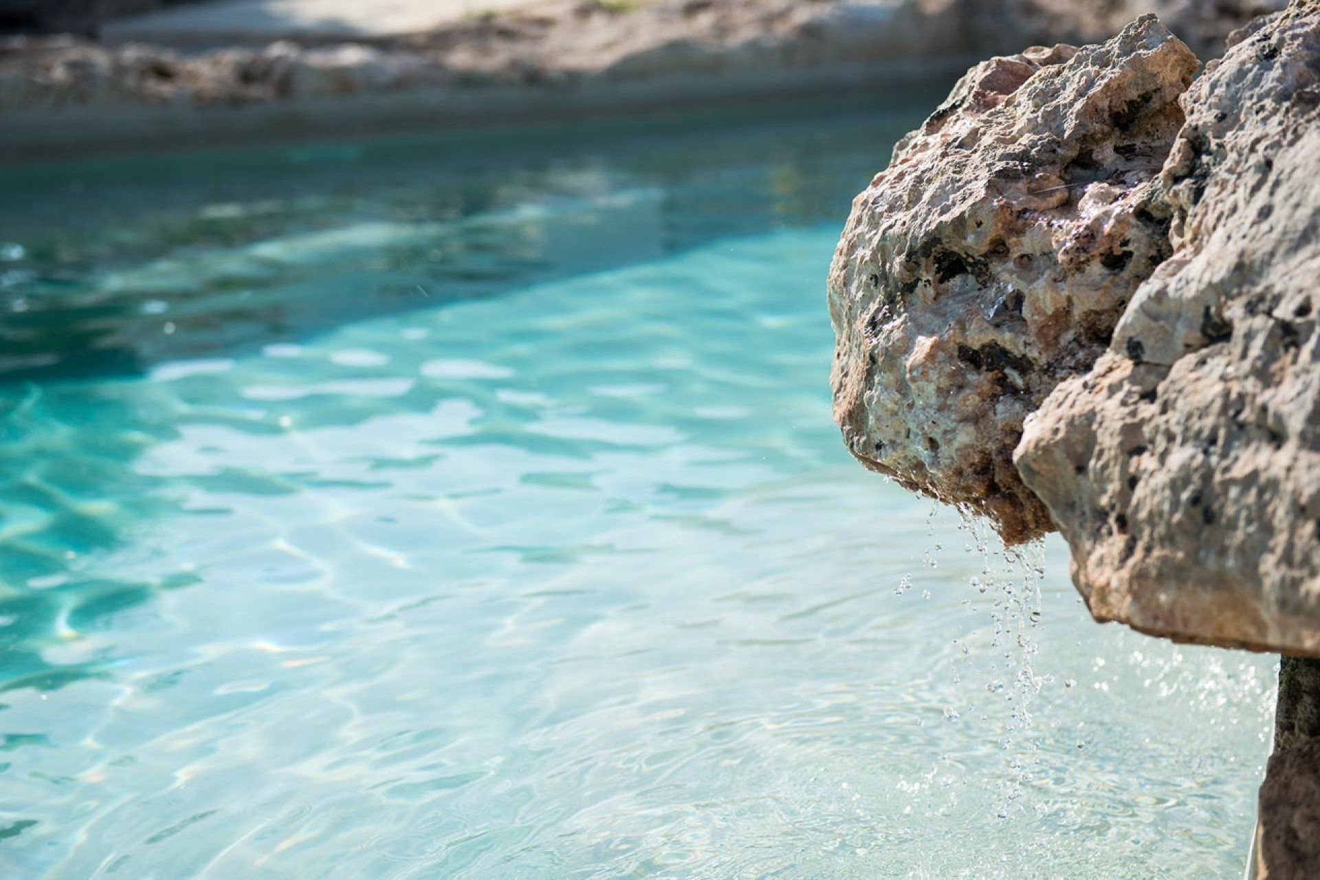 A clear blue pool with a rocky edge.
